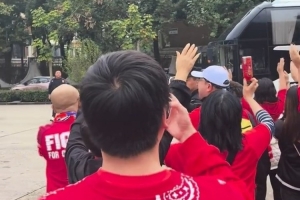 球迷?shī)A道歡迎重慶銅梁龍球隊(duì)大巴，并高舉雙手喊“重慶雄起！”
